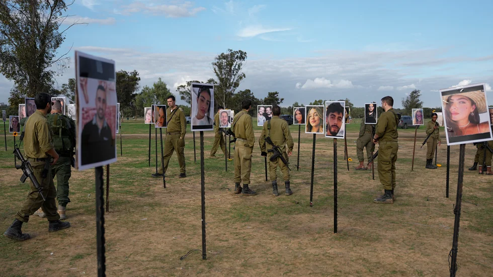 Israeliska soldater och andra går omkring bland bilder på människor som dödades eller togs gisslan av Hamas under den blodiga attacken mot Israel den 7 oktober.