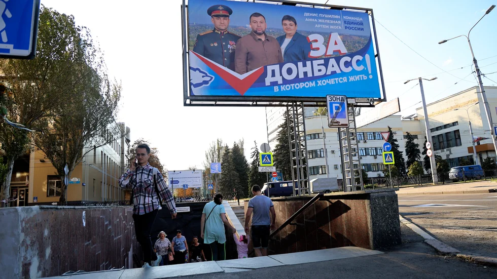 Människor vid en tunnelbanenedgång nära en rysk valaffisch i Donetsk.