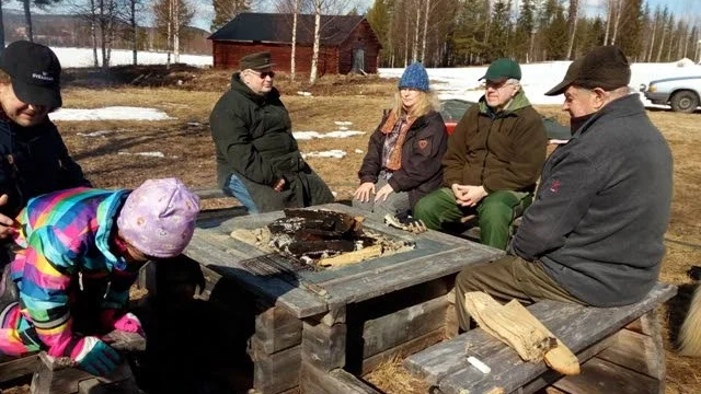 Vid grillen. På stranden sitter Sören Nilsson och några till som har fikapaus och grillar korv.
