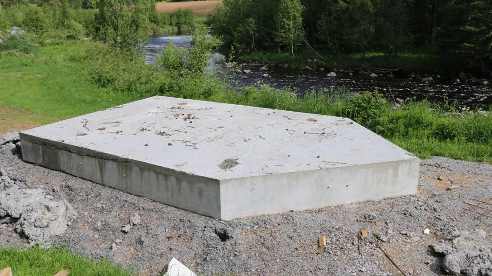 En av betongplintarna ligger färdig och ska lyftas ner i vattnet av en kranbil.