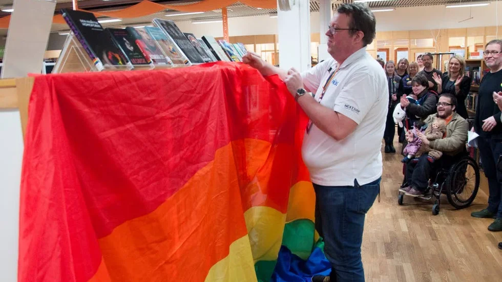Invigning. Jimmy Berg från RFSL Piteå drar regnbågsskynket från den nya hyllan.