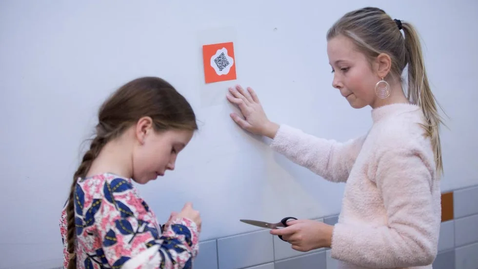 Olivia Berggren och Agnes Franzén sätter upp QR-koder som innehåller kloka ord.