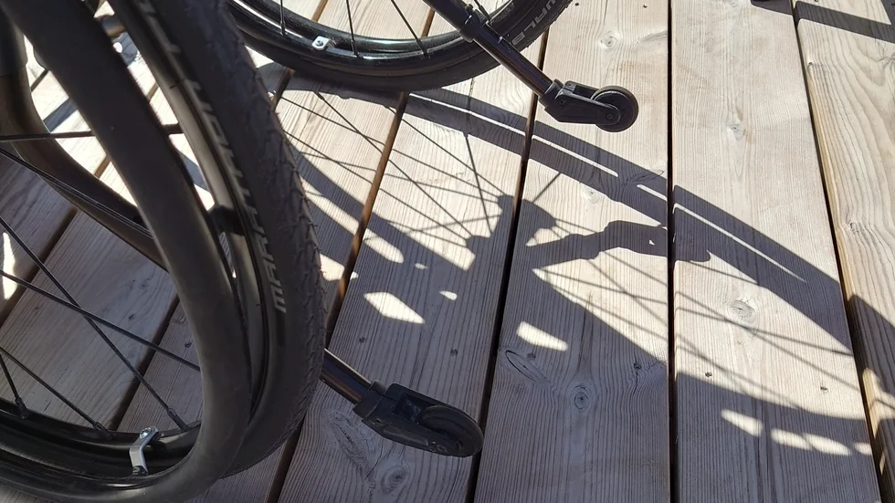 Skuggan av en rullstol på ett trädeck.