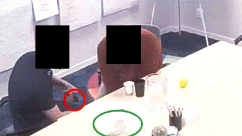 Här sker mötet då flera föremål lämnas över till den grovt kriminelle mannen. Ur en benficka tar kriminalvårdaren fram något som mannen smusslar ner i en svart påse, under bordet.