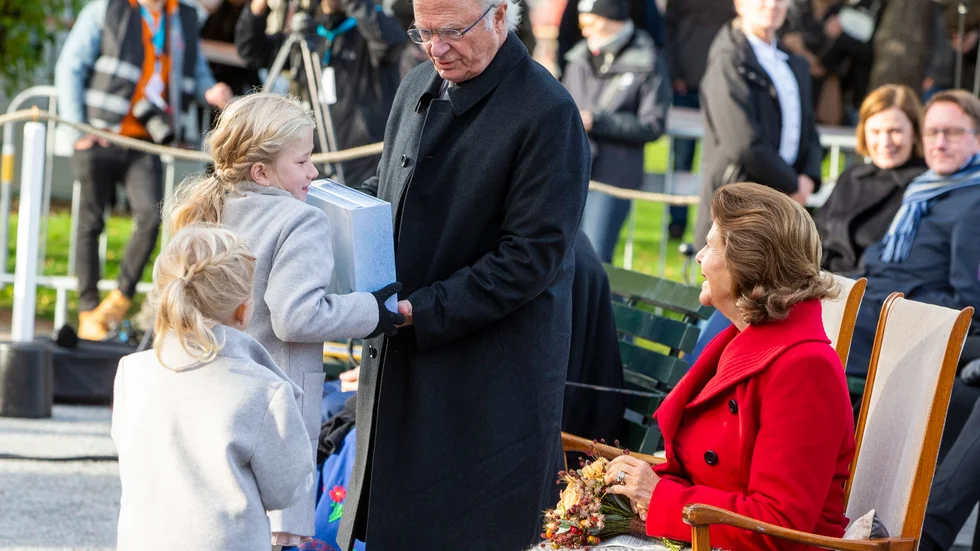 Kungaparet fick ta emot en tung present, Ebba Wäppling lämnar över bokverket som väger 5,1 kilo till kungen. Lillasyster Judith och drottning Silvia ser på.