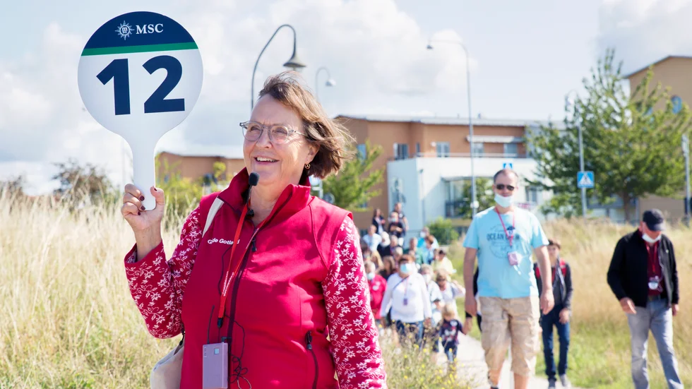 Gotlandsguiden Annabritta von Schulman har en handhållen skylt som det står nummer tolv på. Samma siffra står på gruppens turistbuss och även på kryssningsturisterna, som har runda klisterlappar på tröjorna.