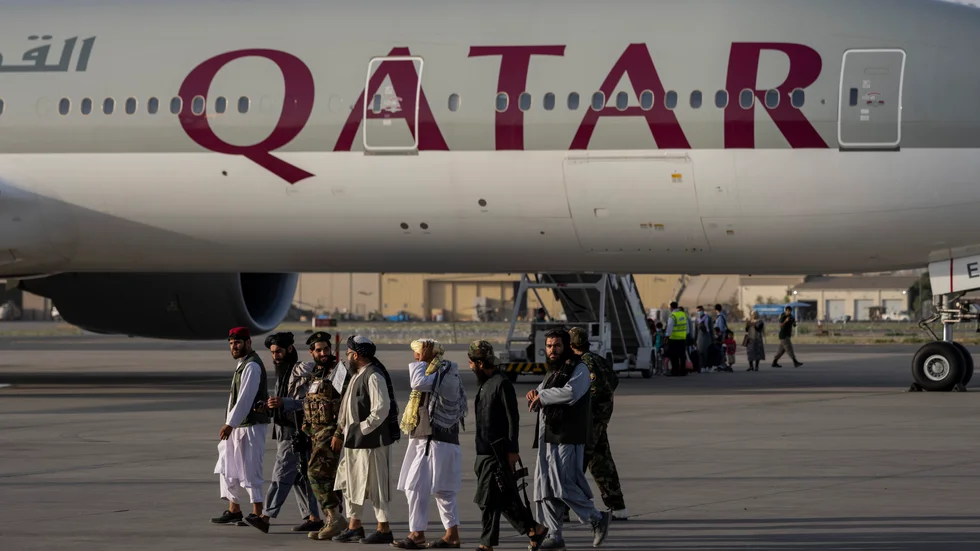 Talibaner promenerar förbi det plan som lyfte från Kabuls flygplats på torsdagen.