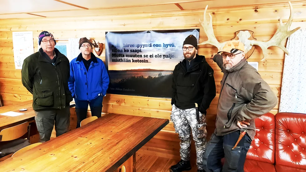 I stugan vid Vittangi älgskyttebana frinns denna banderoll uppsatt. På bilden syns, från vänster Lage Woutilainen ordförande, Roger Ögren banchef, Simon Engström jägare och Håkan Lundström, jägare. "Den största delen av vår jägarkår pratar meänkieli så visst är det av stor betydelse att språket får utrymme och också syns, inte bara hörs".