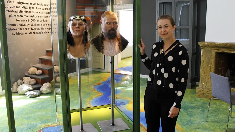 Museiintedent Camilla Gullin med rekonstruerade modeller av stenåldermänniskor. 