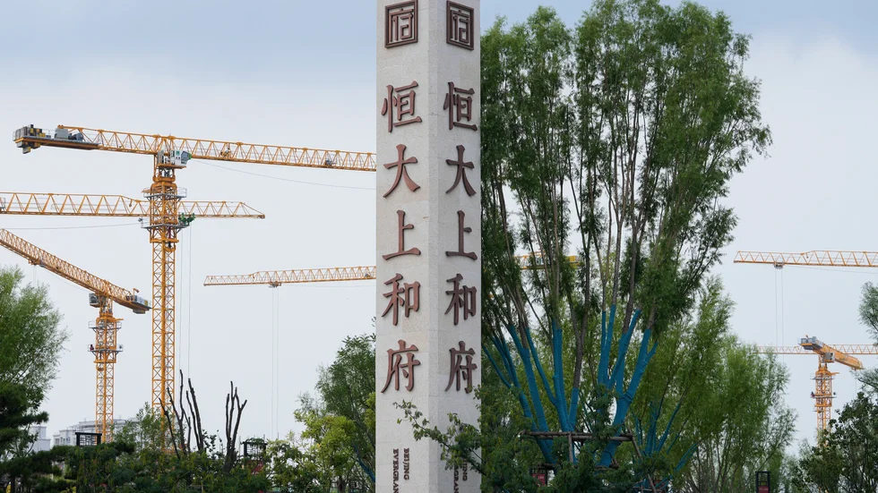 Byggkranar syns bakom en skylt med Evergrandes namn och logga vid en byggarbetsplats i Peking.