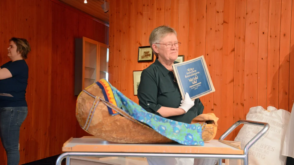Ann-Kristin Öberg visar upp nygamla föremål som museet fått in. En gietjam, babysäng, med Arjeplogs samiska snitt samt en gammal telefonkatalog.
