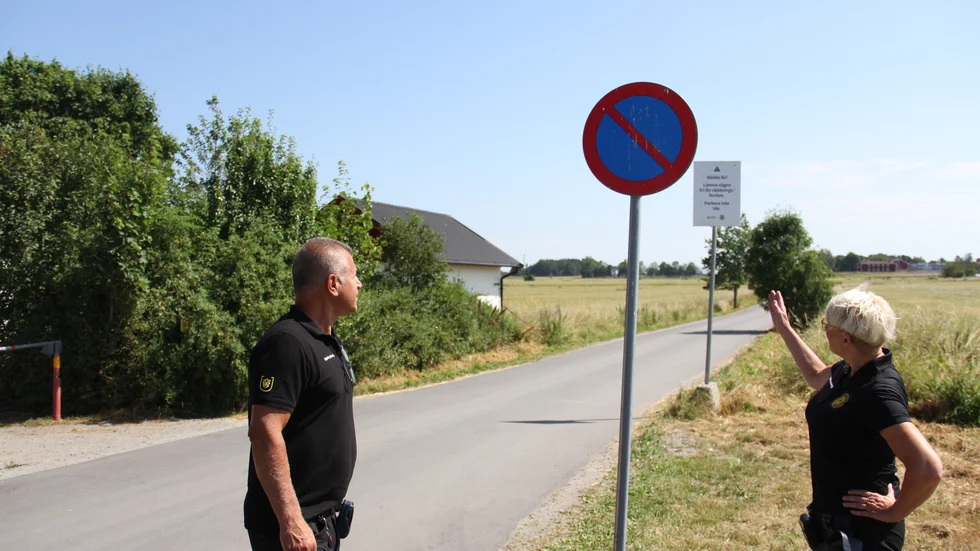Parkeringsvakterna Kurosh Nowroozi och Åsa Mossberg visar var man inte får parkera vid Storvadsbadet. Om bilar står felparkerade på den smala vägen kan det bli svårt för räddningsfordon att ta sig fram.