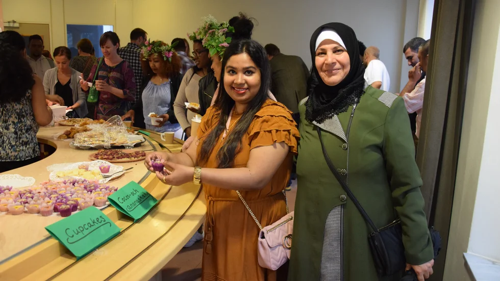Dil Akhiay Jaham (t v) från Bangladesh bjuder Haifa Ahmab från Irak på hembakt fika vid torsdagens sommarfest på SFI i Skellefteå.