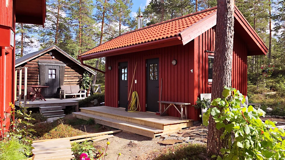 Friggeboden rymmer ett gästrum och en bastu som ska bli klar under hösten. Längst bort står den inredda ladan, som fungerar som gäststuga.