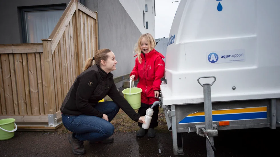 Anette Lindholm fyller på vatten och får hjälp av dottern Edith.