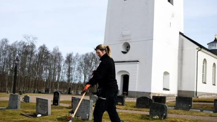 Kyrka mitt i byn. Jane Ljung arbetar     som kyrkvaktmästare och har ansvaret utomhus.