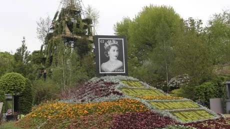 Drottning Elizabeths 60 år på tronen uppmärksammas naturligtvis också på Chelsea Flower Show. En rejäl blomsterkulle kröntes med ett kungligt frimärke. I bakgrunden trädgårdsdesigner Diarmuid Gavins sjuvåningstorn. En pyramid tänkt för både odling och avkoppling i staden.Foto: Gunnel Carlson