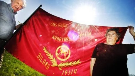 Makarna Bertil och Else-Marie Persson i Edsbruk med den äldsta fanan som finns i Bruksgården. Den är från när den socialdemokratiska föreningen bildades 1914. Bilden togs för exakt ett år sedan, den 29 april 2009.Foto: Ellen Kindstrand
