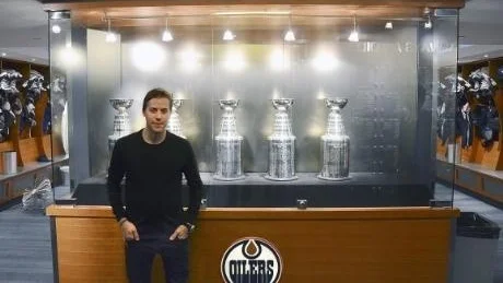 Linus Omark poserar framför Edmonton Oilers prisskåp.