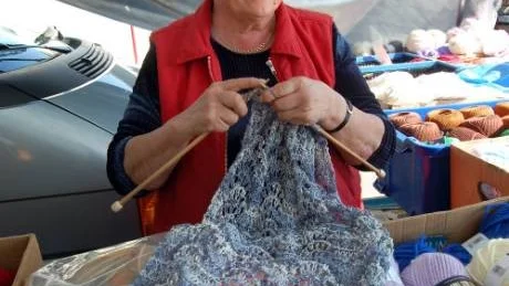 STICKAR OCH SÄLJER. Gunvor Lundin, Umeå, en av 35-talet knallar på Sangis marknad, passade på att sticka medan hon sålde garner och handarbeten.