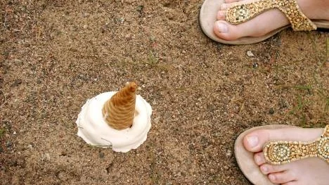 En varm dag på stranden och en god glass i handen förvandlas snabbt till smält glass i sanden.