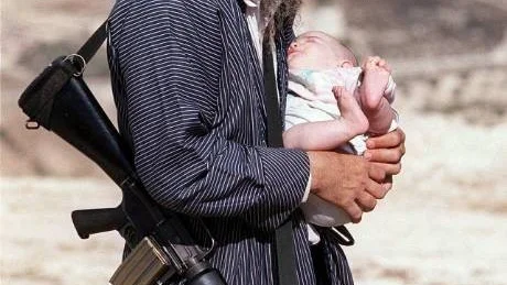 JER14 - 20001011 - YITZHAR, WEST BANK, - : An armed ultra orthodox Jewish settler holds his baby as he attends the funeral of Hillel Lieberman in the Jewish settlement of Yitzhar near Nablus in the West Bank, Wednesday 11 October 2000. Lieberman, a distant cousin of US Democratic vice presidential hopeful Joseph Lieberman, was found shot dead in the West Bank, a victim of the wave of Israeli-Palestinian violence. Lieberman, a 37-year-old US citizen, had been living in the West Bank settlement of Elon Moreh, and attended the yeshiva college at a Jewish shrine known as Joseph's Tomb in Nablus which was destroyed by angry Palestinians at the weekend. 
EPA PHOTO AFP/MENAHEM KAHANA Code: 455
COPYRIGHT PRESSENS BILD