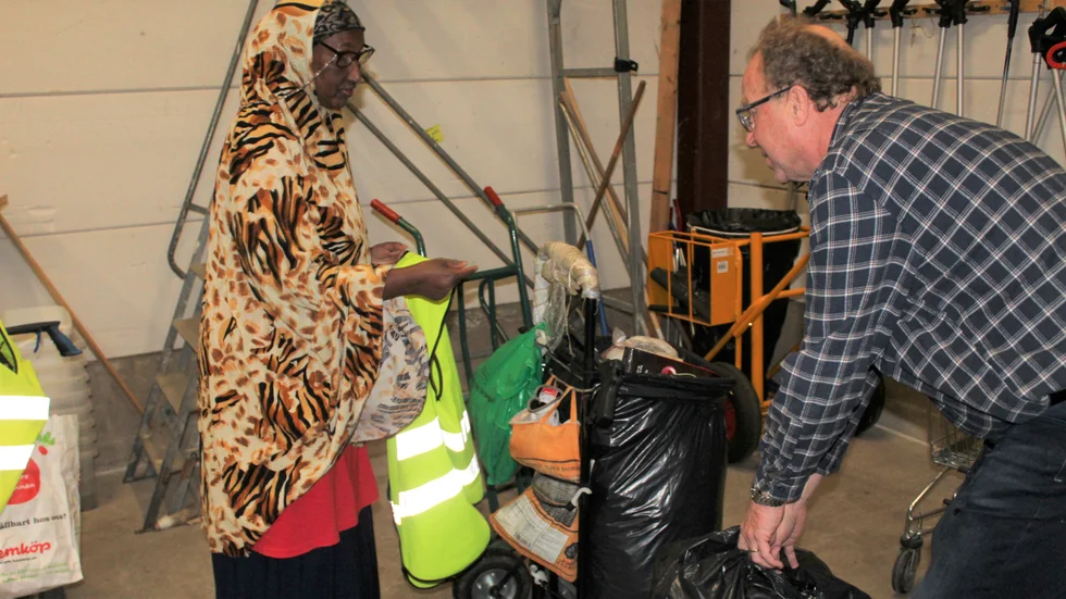 Sahro Hussein, miljövårdare, och Mikael Almgren, arbetsledare, väger skräpet som Sahro samlat in under måndagen. Vågen visar 13,5 kilo. 