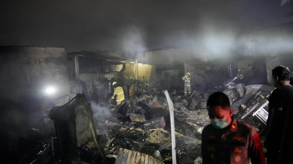 Brandmän inspekterar nedbrunna hus i Jakarta under tidig natt till lördag, lokal tid.