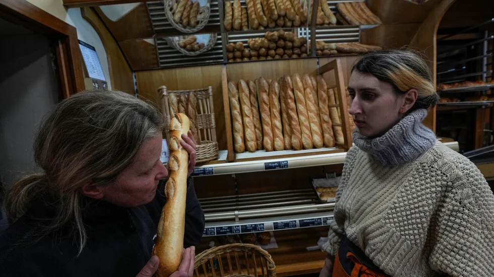 Bageriägaren Florence Poirier, till vänster, luktar på en nybakad baguette som Mylène Poirier just har tagit ur ur ugnen, på bageriet i Versailles utanför Paris.