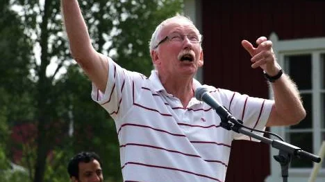 Poeten Sven Nyberg står vid mikrofonen under helgens tävling på Kulturgården. Hans humoristiska framträdande inkluderade hela kroppen, vilket tycktes roa medtävlanden Samed Salman som sitter i bakgrunden och väntar på sin tur.
