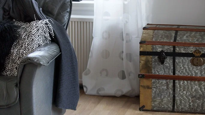 Lädersoffa och kista från Myrorna, kuddar och sittpuff från Makaroom samsas i vardagsrummet.