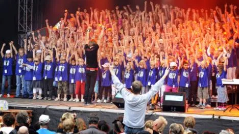 Invigningen med rock"n rollkörens 207 barn fick festivalbesökare att samlas framför stora scenen. Kören leddes av Peter Tikkanen som lagt möda på att ge de sångglada barnen stort utrymme.