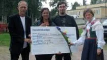 Sonja Wiklund-Falck, ordförande i den lokala hembygdsföreningen delar ut check och blommor till Årets malmbergare, fr v Ove, Berith och Mattias Kalander