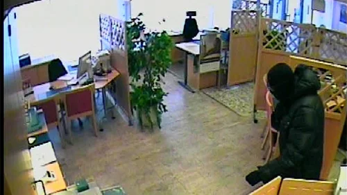 Rånaren söker igenom lådor i kontorslandskapet.