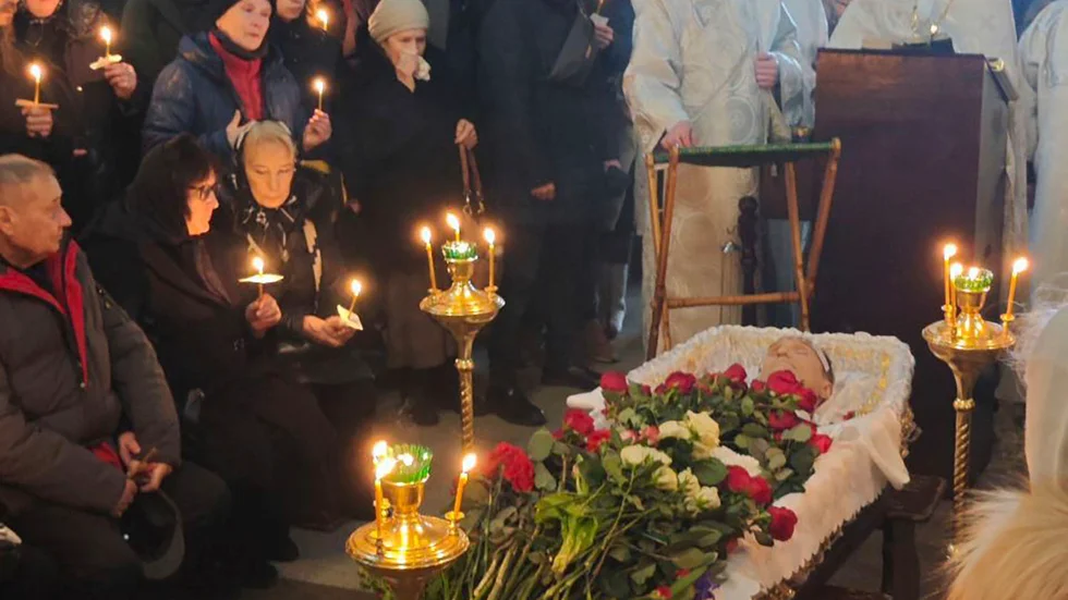 Aleksej Navalnyj i kistan under fredagens begravning. Vid hans sida sitter hans föräldrar.