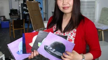 Yui Mihara visar upp några av de bilder hon skapat på Konstskolan som också var hennes bidrag till den samlingsutställning eleverna visat på Konstmuseet. Nu är det mycket osäkert om hon får klartecken från migrationsverkets att återkomma och göra klart sina studier.