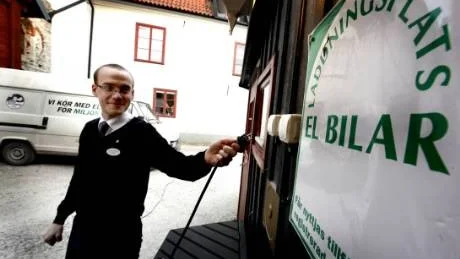 Tankställe. Hotellet har ett uttag för laddning av elbilar. I bakgrunden står S:t Clemens egen elbil som används för hotellets transporter. Hotellet använder vindkrafts-el.