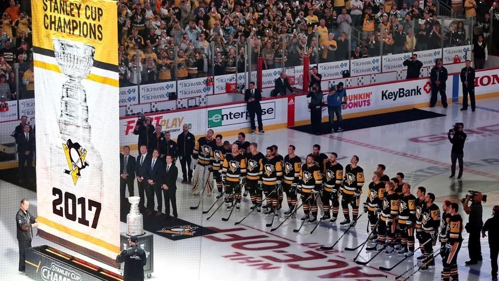 Members of the Pittsburgh Penguins watch as the banner for their fifth Stanley Cup Championship is raised before the NHL hockey game against the St. Louis Blues, Wednesday, Oct. 4, 2017, at PPG Paints Arena in Pittsburgh. (AP Photo/Keith Srakocic)