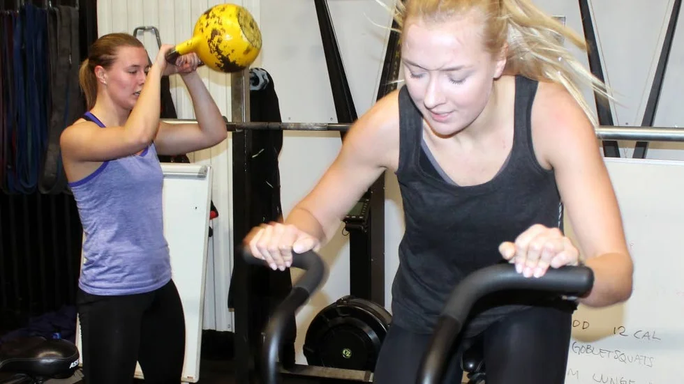 FULLT ÖS. Sara Derelöv och Alexandra Struwe är träningskompisar på Crossfit Motala. "Jag älskar att vara här, vi är som en familj", säger Struwe, här på assaultbiken.