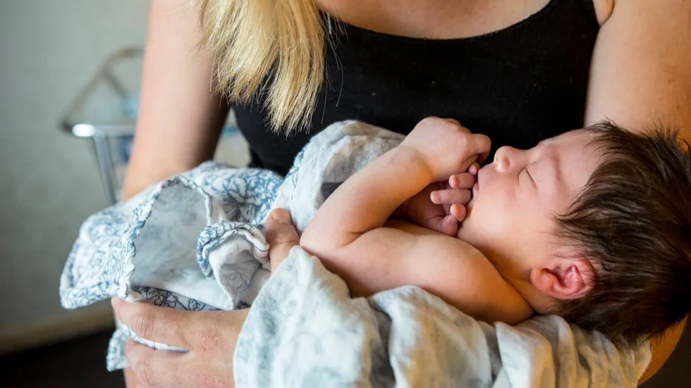 Genrebild.  En nyfödd bebis i sin mammas famn.