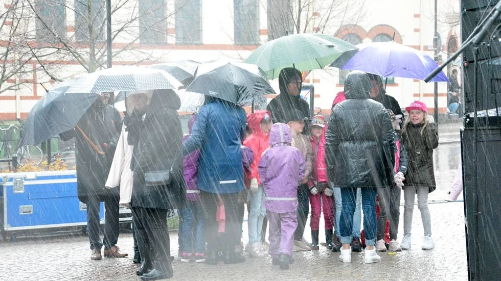 Barnkören från Ljungbergaskolan väntar på att få uppträda, och regnet bara öser ner.