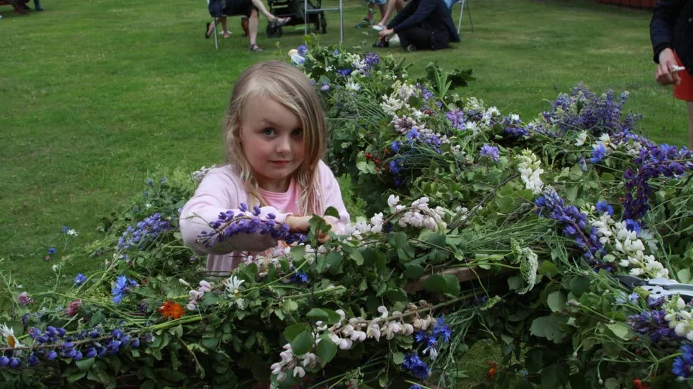 Veta gammelgård. Lottie Käll hjälpte till att klä midsommarstången med blommor.