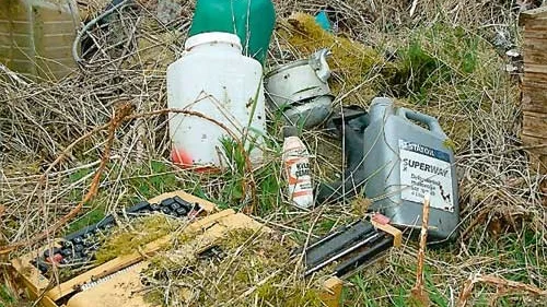 En skrivmaskin och kylarcement jämte några av de mängder av dunkar med rengöringsvätskor och oljor som någon slängt.