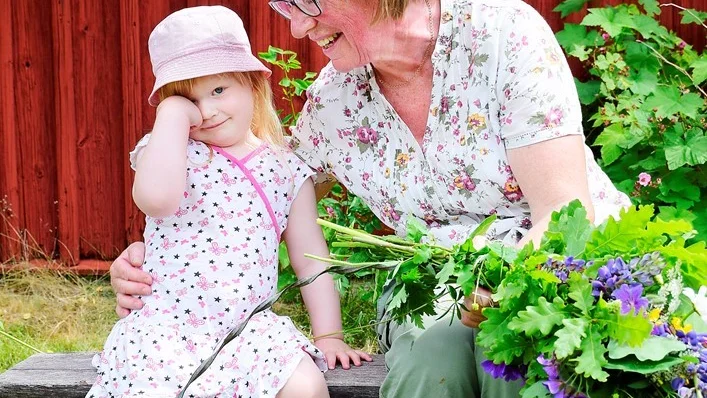 Gerd Segerström med barnbarn Moa Segerström sitter och binder en av kransarna till midsommarstången. Foto: Elin E Elmström