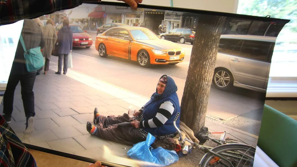 Kontraster. En kvinna sitter och tigger bredvid en väg.