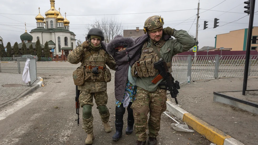 Ukrainska soldater hjälper en kvinna i staden Irpin söndag den 6 mars.