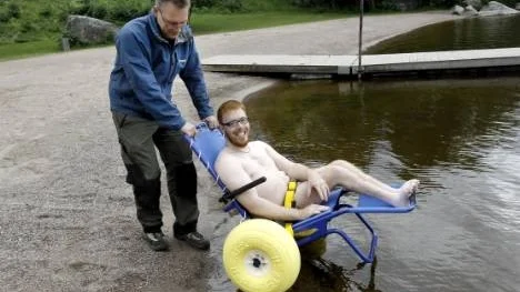 Mattias Ahlén testar badrullstolen med hjälp av Joakim Jansson.