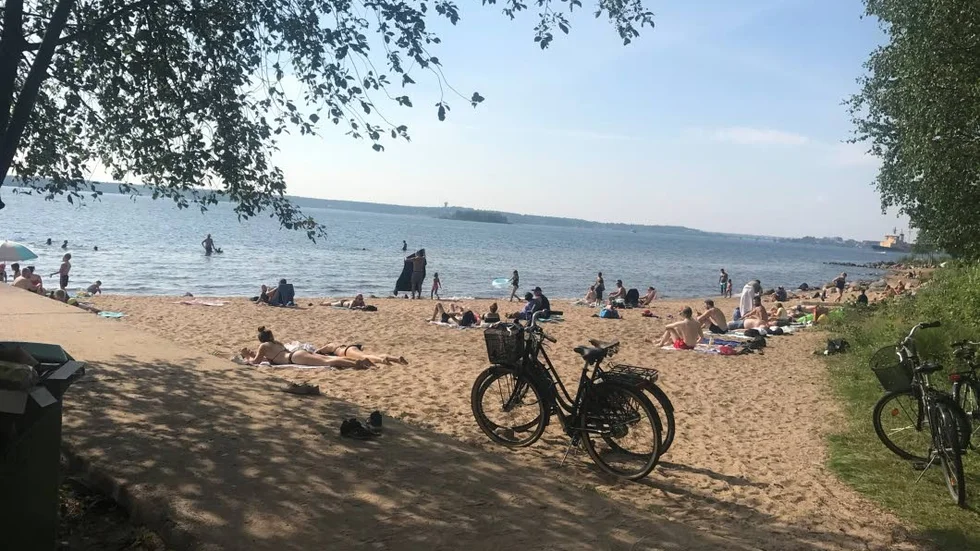 En välbesökt strand i Svartöstaden under en varm sommardag.