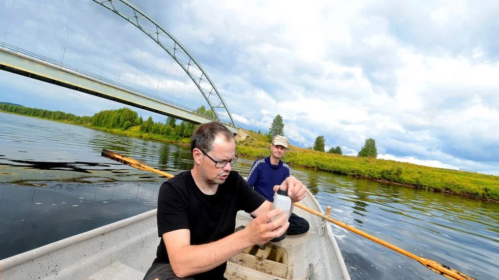 Vita fläckar på Ängesåns yta i byn med samma namn som vattendraget oroar fiskare och andra. Fredrik Nordblad vid Länsstyrelsens Miljöanalysenhet tog därför prover på vattnet. Båtskjuts fick han av bybon Clas Jacobsson.