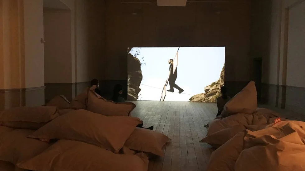 Lindansarkonst. Lindansare rör sig på höga höjder i en videoinstallation på Konstmuseet.